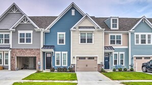 A row of townhouses with a garage, a stone facade, and a well-maintained lawn.