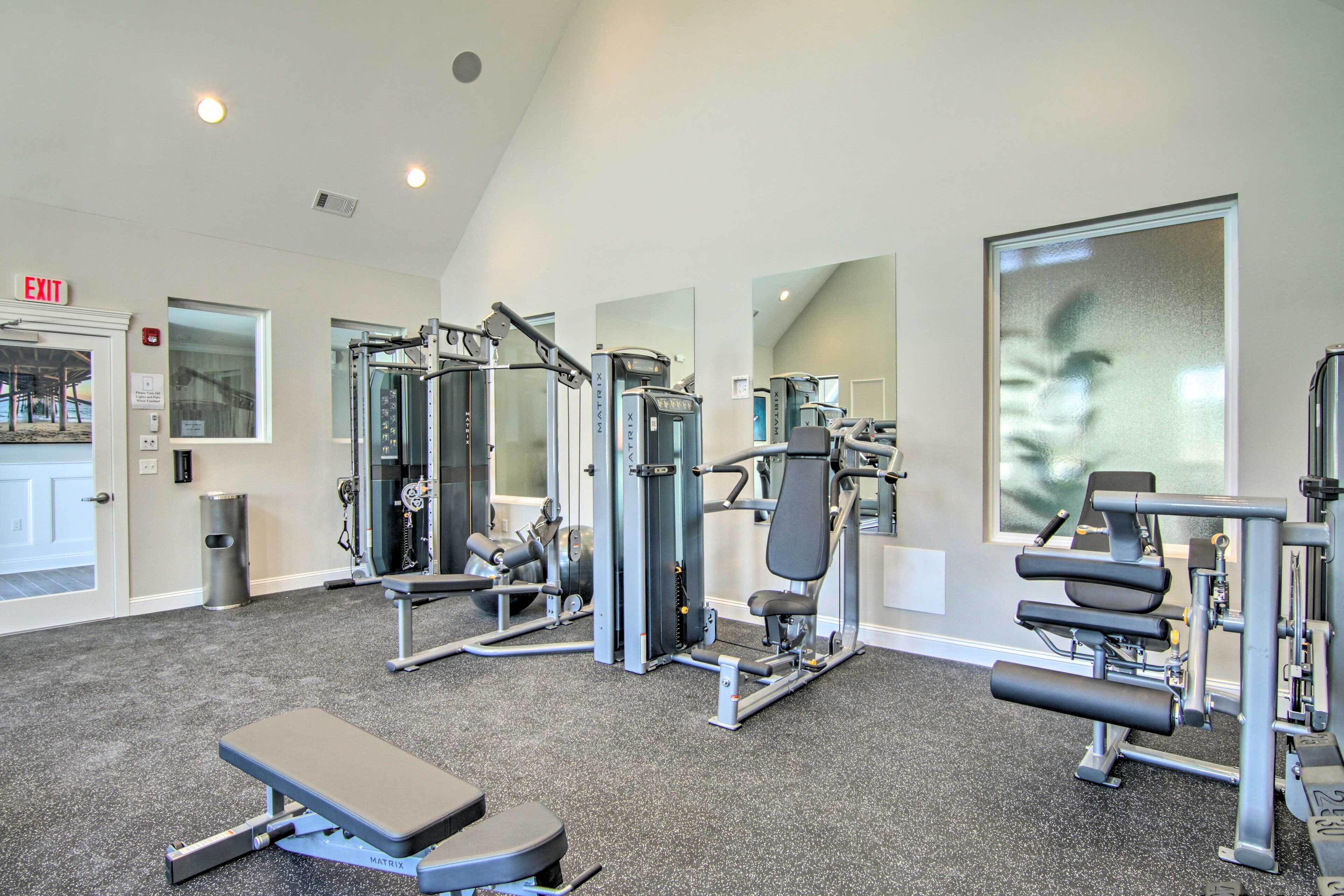 A gym with various exercise machines, a bench, and a large mirror.