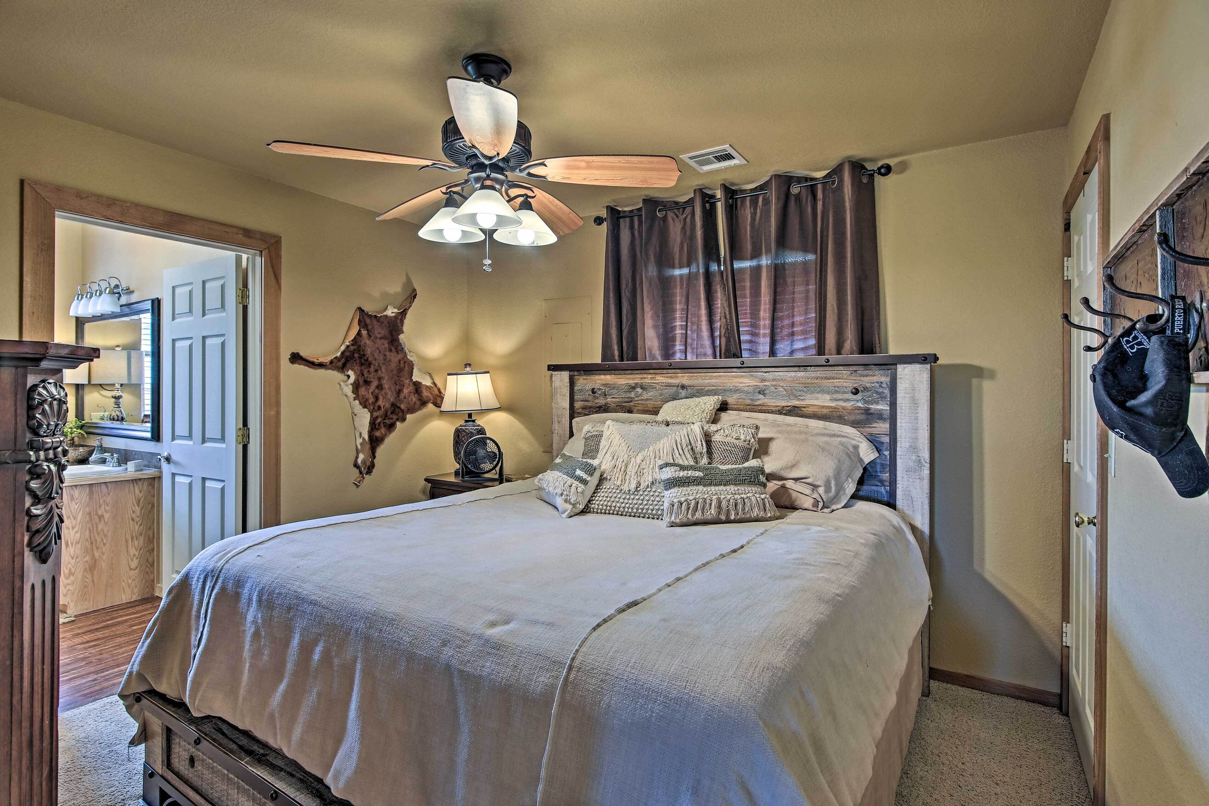 A bedroom with a bed, a ceiling fan, a wall-mounted clock, a coat rack, and a door.