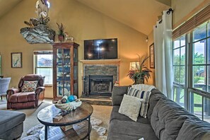 A cozy living room with a fireplace, leather armchair, and a large window. - Charming Vian Retreat w/ Private Deck & Grills! (Vian)