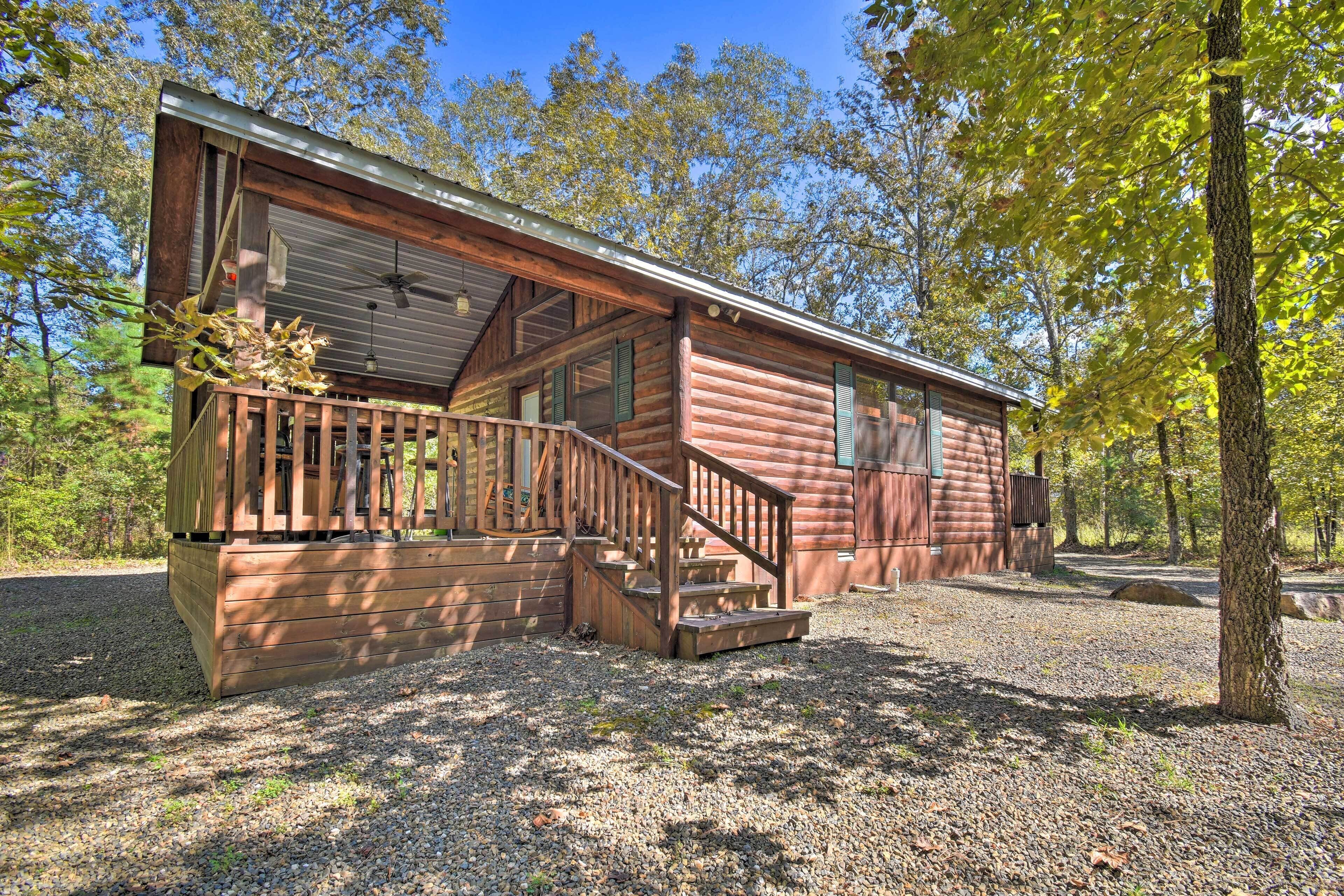 A log cabin with a wooden deck and a staircase leading to the entrance.