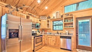 A modern kitchen with wooden cabinets, stainless steel appliances, and a large window. - Broken Bow Hideaway w/ Hot Tub & Fire Pit! (Broken Bow)