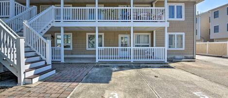 A two-story building with a covered porch, a staircase, and a parking lot marked with numbers.