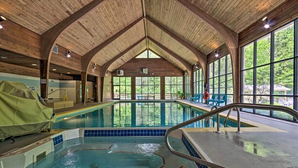 Une piscine intérieure dotée d’un plafond en bois et de grandes fenêtres.