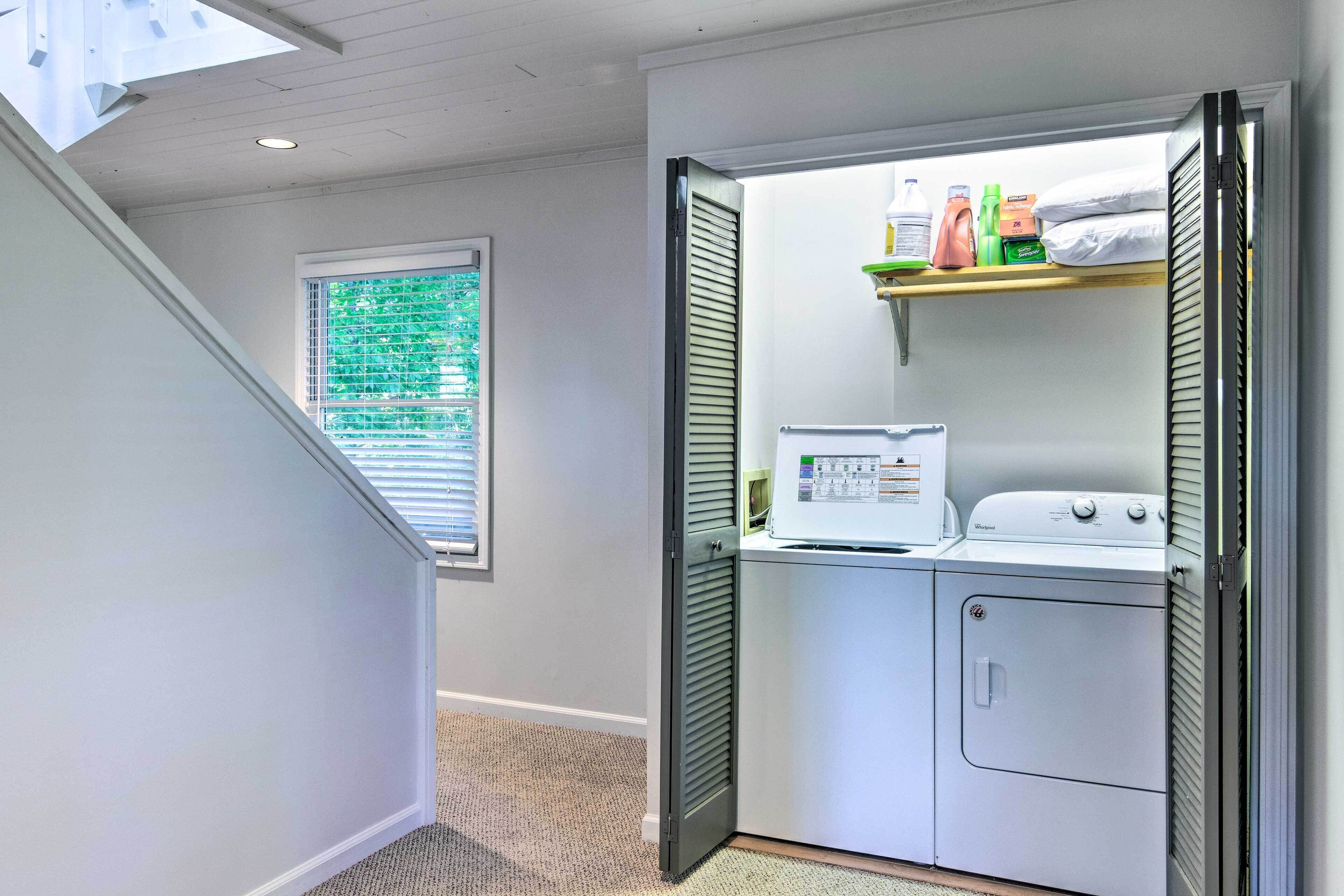 A laundry room with a washer and dryer, a shelf with cleaning supplies, and a window with blinds.