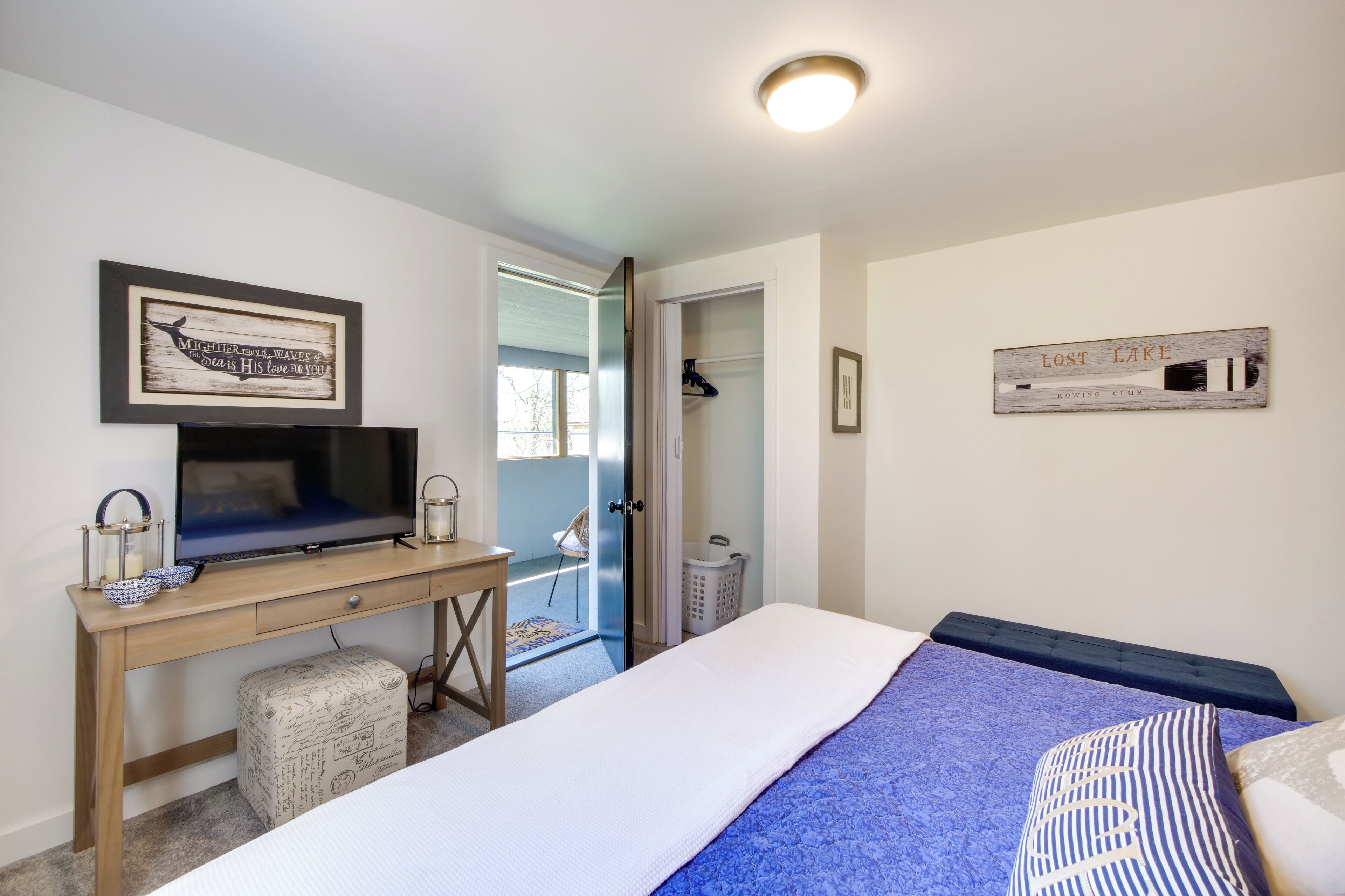 A bedroom with a bed, a desk with a TV, a wardrobe, and a wall-mounted sign.