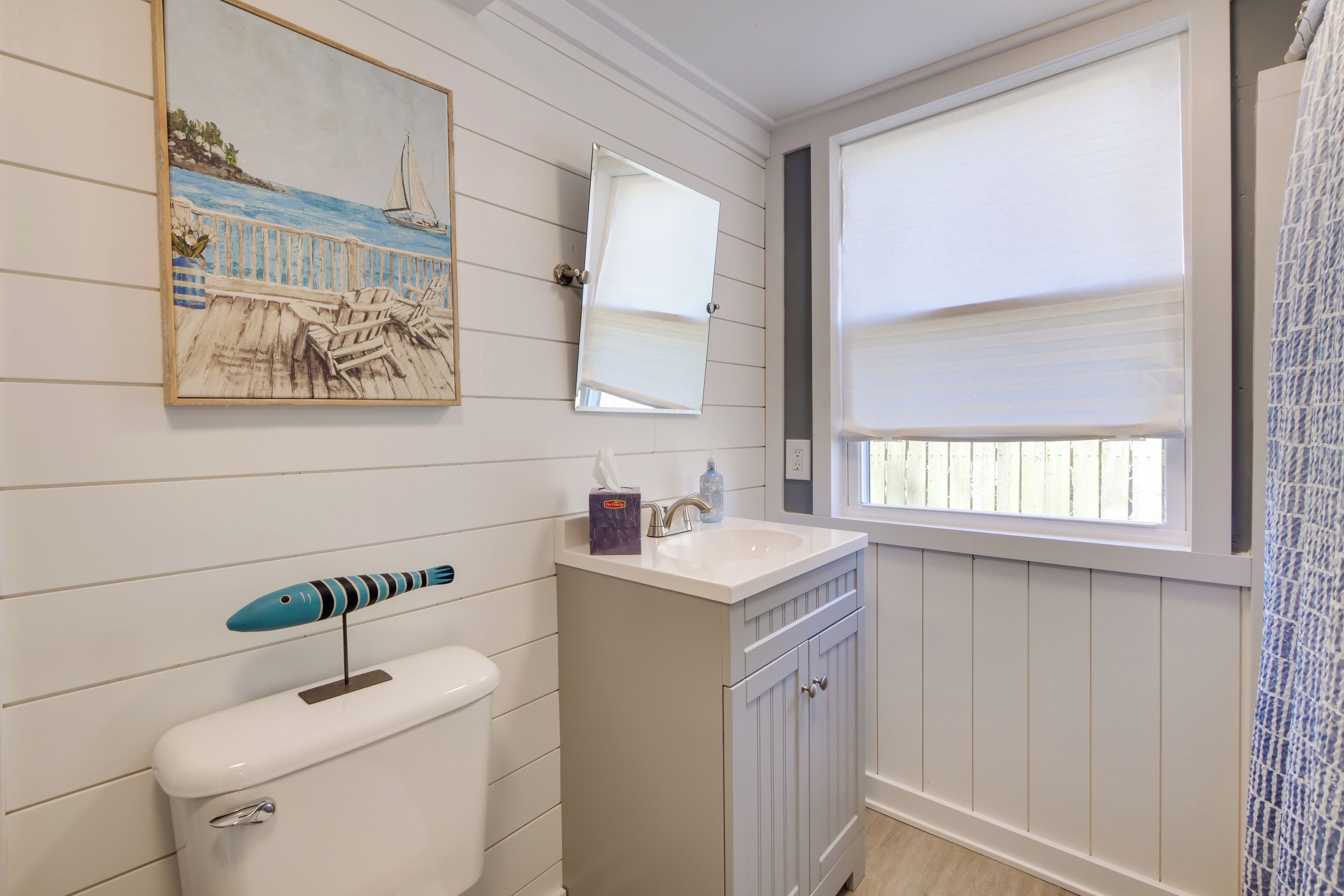 Un baño con inodoro, lavamanos y ventana con persianas.