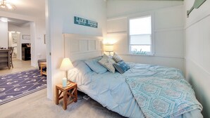A bedroom with a bed, a nightstand, a lamp, a window, and a sign reading 'LAKE HOUSE.' - Walk to Lake: Nautical Akron Cottage w/ Deck! (Akron)