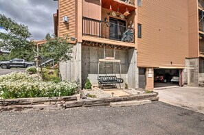 A multi-story building with a balcony, a bench, and a parking garage. - Brian Head Condo w/ Shared Pool & Hot Tub! (Brian Head)