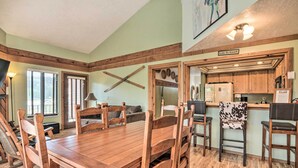 A dining area with a wooden table and chairs, a kitchen area with wooden cabinets, and a sign that reads "Life is Good". - Brian Head Condo w/ Shared Pool & Hot Tub! (Brian Head)
