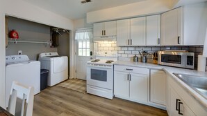 Une cuisine compacte avec des meubles blancs, un four à micro-ondes, une cuisinière et un lave-linge.