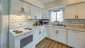Une cuisine moderne avec des armoires blanches, une cuisinière en acier inoxydable, un four à micro-ondes et un lave-vaisselle.