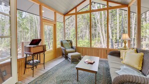 Une pièce chaleureuse avec un plafond en bois, de grandes fenêtres, un canapé, une table et une chaise.