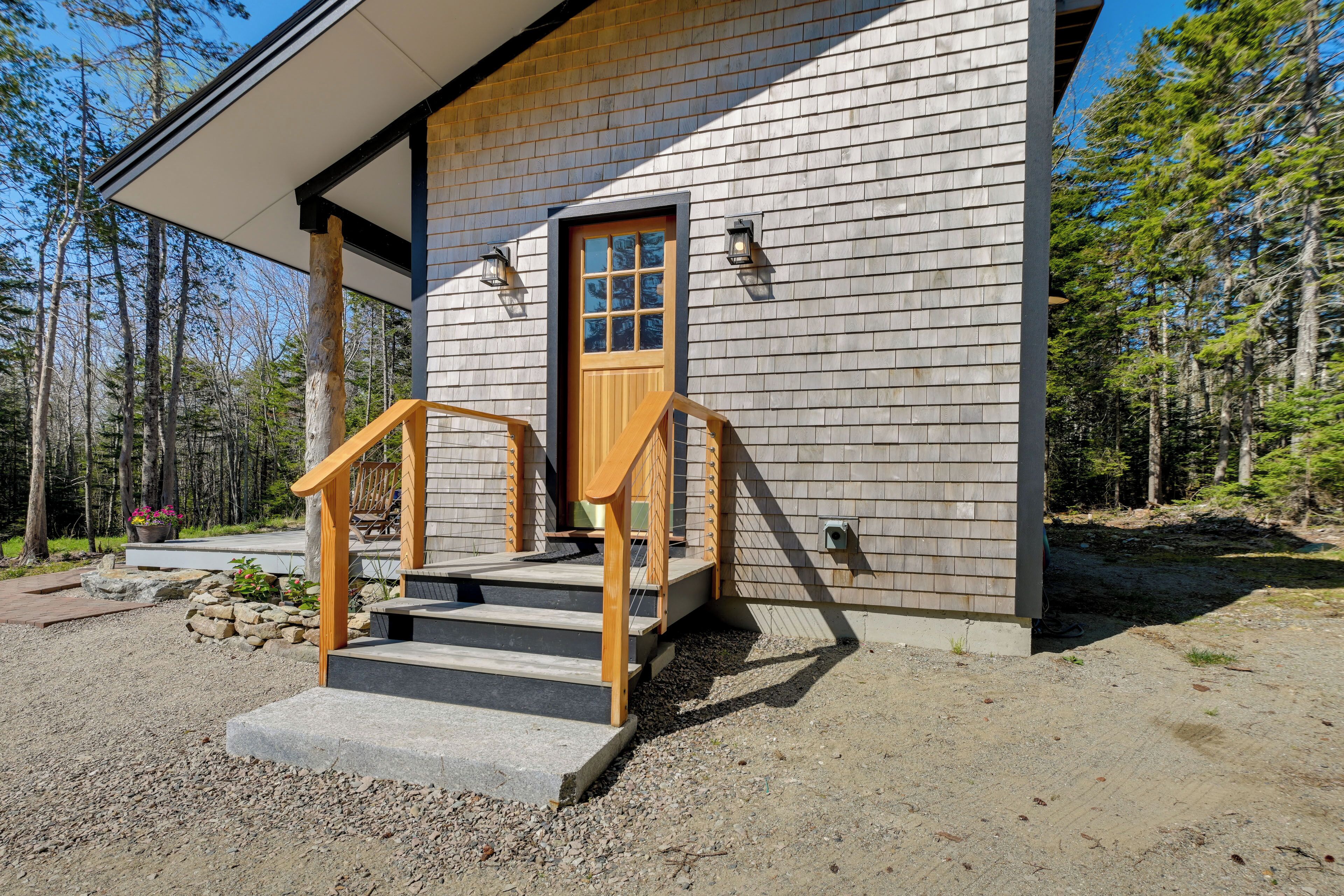 Une cabane en bois avec un porche à l’avant, des marches et une porte.
