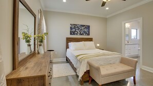 Ein Schlafzimmer mit einem Holzkasten, einem Bett mit weißer Bettwäsche, einem Deckenventilator und einem Bild an der Wand.