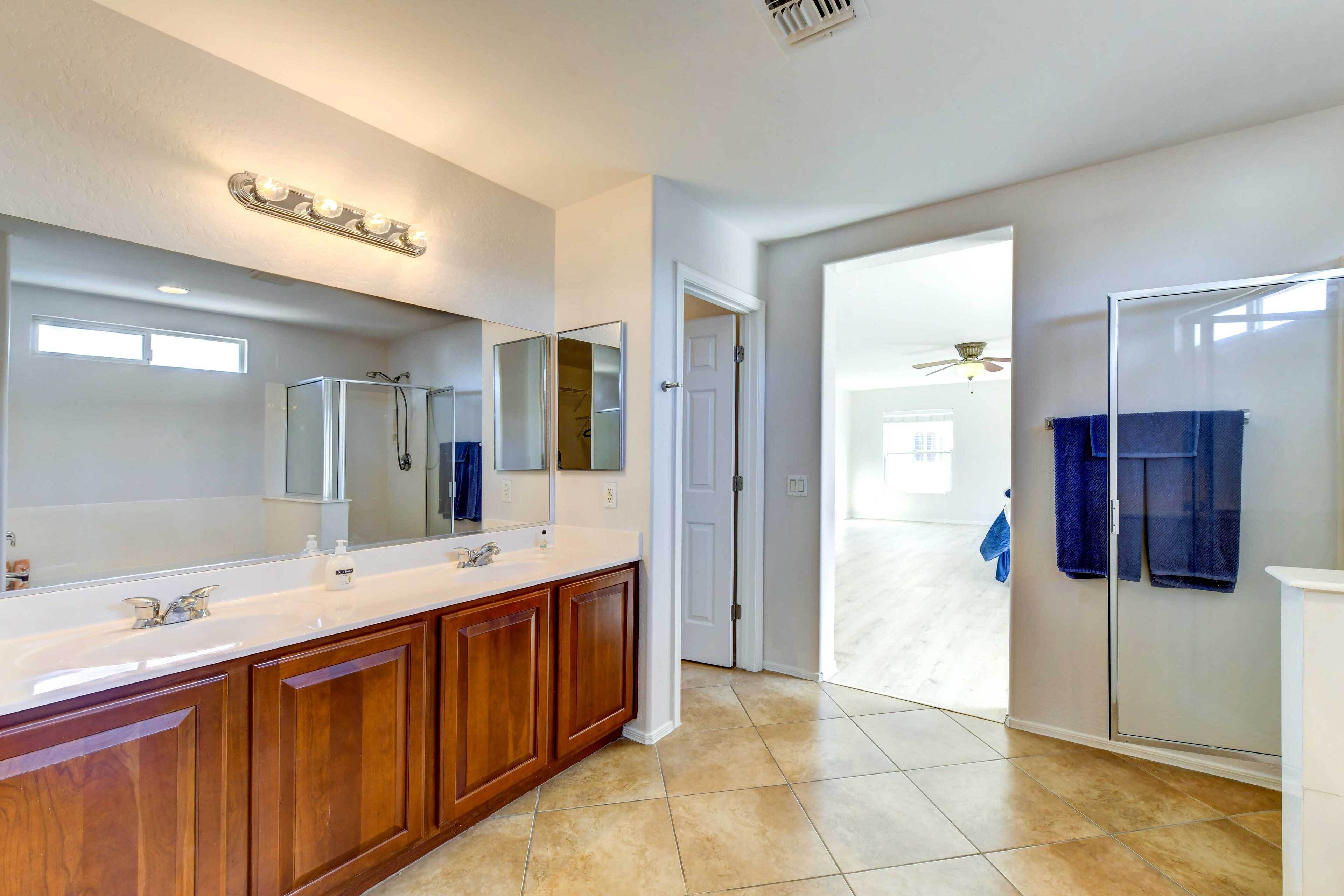 A modern bathroom with a large vanity, a glass shower enclosure, and a walk-in closet.