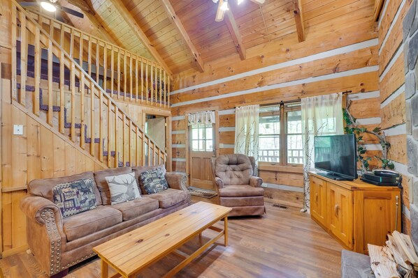 A wooden interior with a sofa, armchair, TV, and wooden staircase. - Gatlinburg Cabin w/ Pool Table ~ 6 Mi to Downtown! (Gatlinburg)