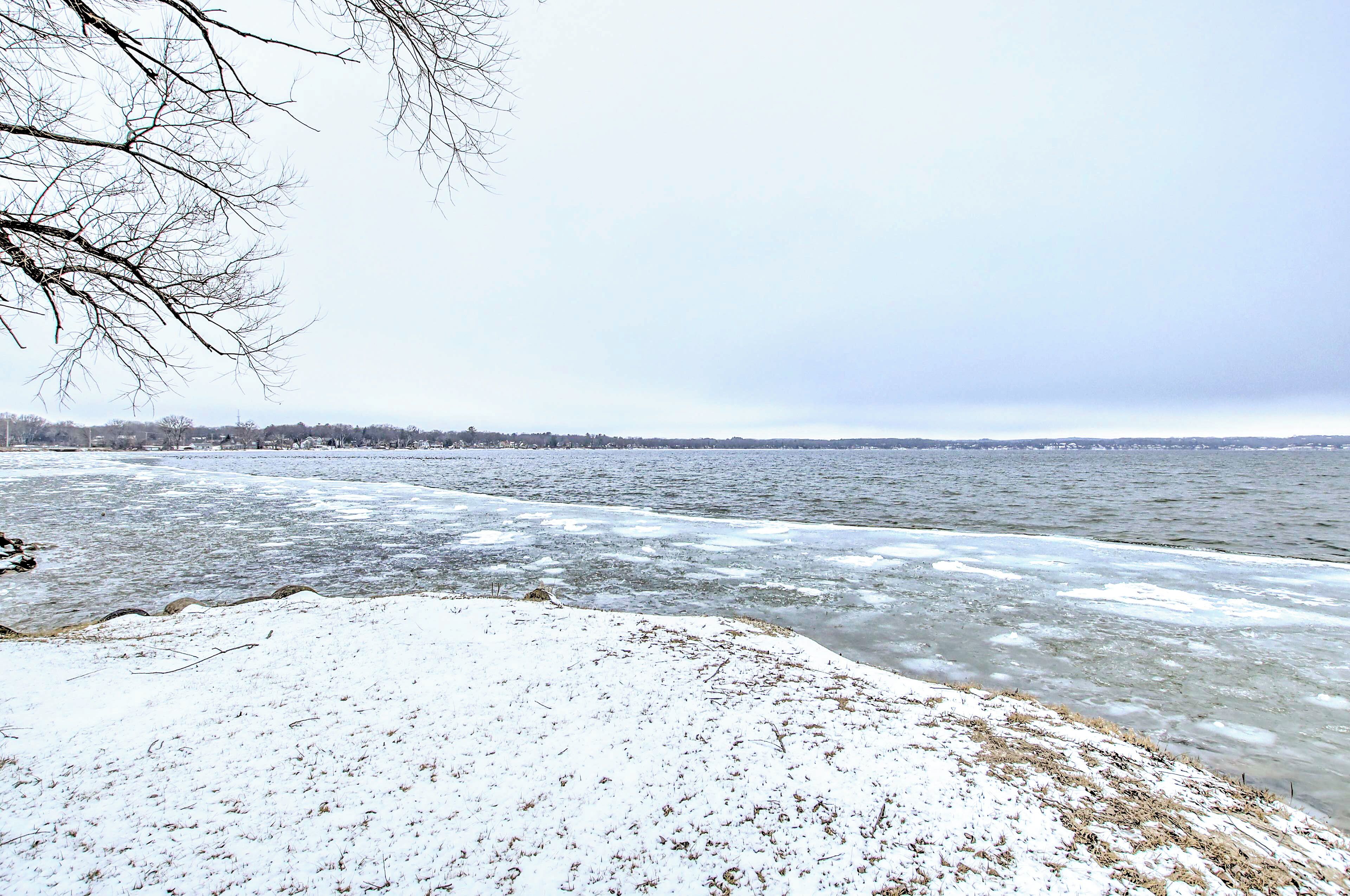 A snowy landscape with a frozen river and a distant city skyline.