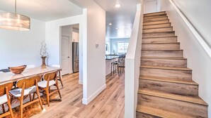 A modern kitchen with wooden flooring, a dining table with chairs, and a staircase with wooden steps. - Spacious Bellemont Cabin w/ Jacuzzi + Mtn View! (Bellemont)