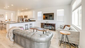 A modern living room with a grey leather sofa, a wooden coffee table, and a bar stool. - Spacious Bellemont Cabin w/ Jacuzzi + Mtn View! (Bellemont)