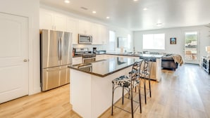 A modern kitchen with white cabinets, stainless steel appliances, and a central island with bar stools. - Spacious Bellemont Cabin w/ Jacuzzi + Mtn View! (Bellemont)