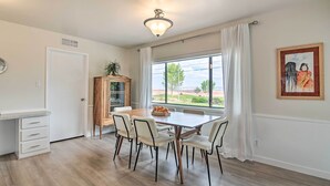A dining area with a wooden table and chairs, a white cabinet, and a window with a view of the outdoors.