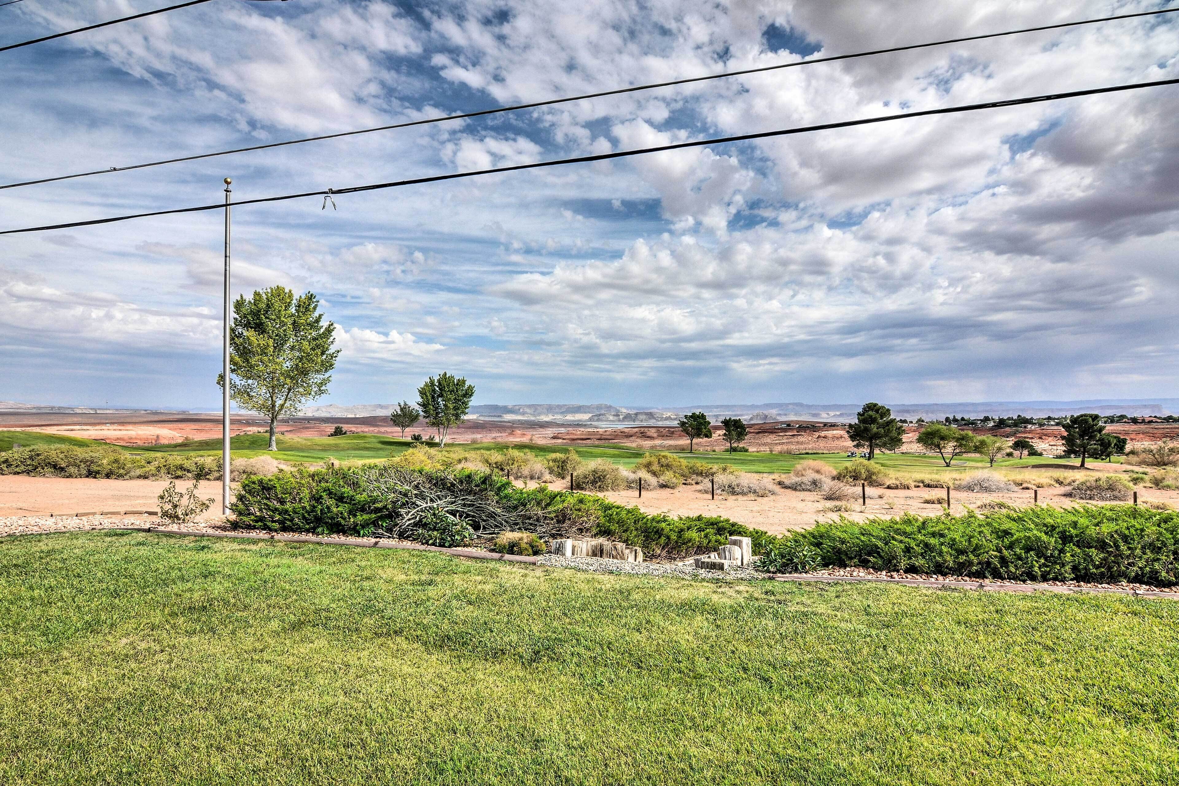 A golf course with a clear sky, power lines, and a variety of trees.