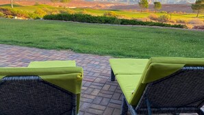 A patio with wicker furniture and a view of a green landscape.