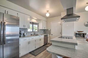 A modern kitchen with stainless steel appliances, white cabinetry, and a central island. - Lake Powell Views: Mid-century Home in Page (Page)