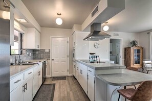 A modern kitchen with white cabinetry, stainless steel appliances, and a central island with seating. - Lake Powell Views: Mid-century Home in Page (Page)