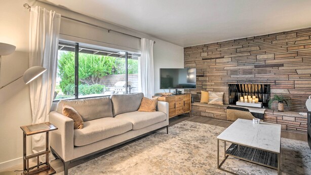 A modern living room with a sofa, a coffee table, a TV, and a fireplace.