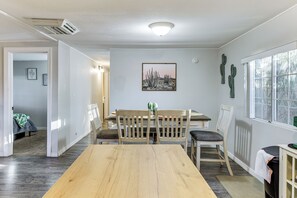 A dining area with a wooden table and chairs, a cactus wall art, and a window with a view. - Updated Escape w/ Game Room 1 Block to River! (Bullhead City)