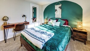 A bedroom with a bed, a desk, a chair, a nightstand, and a wall-mounted tapestry. - Updated Escape w/ Game Room 1 Block to River! (Bullhead City)