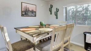 A dining area with a wooden table, chairs, a cactus wall art, and a window with a view. - Updated Escape w/ Game Room 1 Block to River! (Bullhead City)