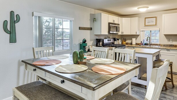 A kitchen with white cabinets, a dining table with placemats, and a cactus decoration. - Updated Escape w/ Game Room 1 Block to River! (Bullhead City)