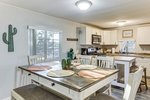 A kitchen with white cabinets, a dining table with placemats, and a cactus decoration. - Updated Escape w/ Game Room 1 Block to River! (Bullhead City)