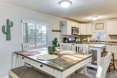 A kitchen with white cabinets, a dining table with placemats, and a cactus decoration.