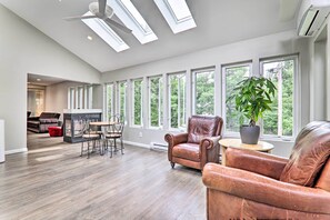 A spacious living room with a fireplace, leather chairs, and large windows offering a view of the outdoors. - Game Room, Pool & Hot Tub: Poconos Paradise! (East Stroudsburg)
