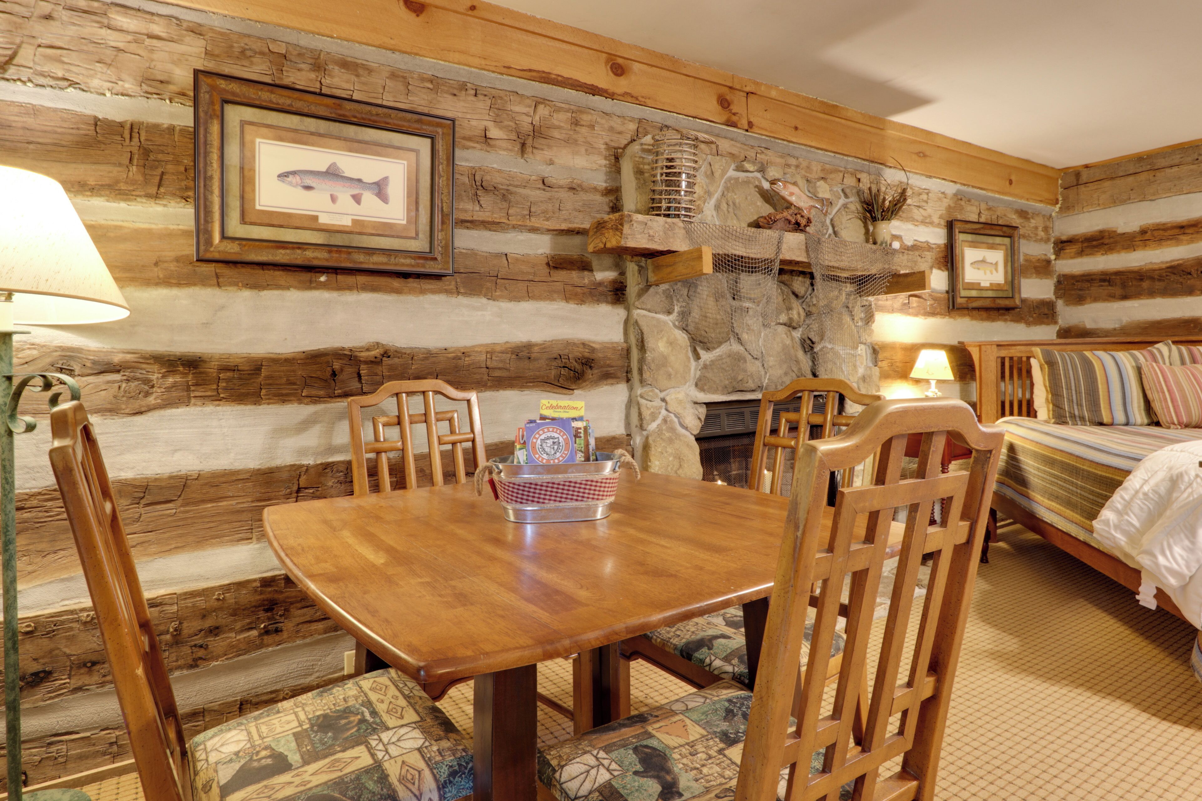 Una stanza rustica con un tavolo da pranzo in legno, sedie, un letto e un camino in pietra.