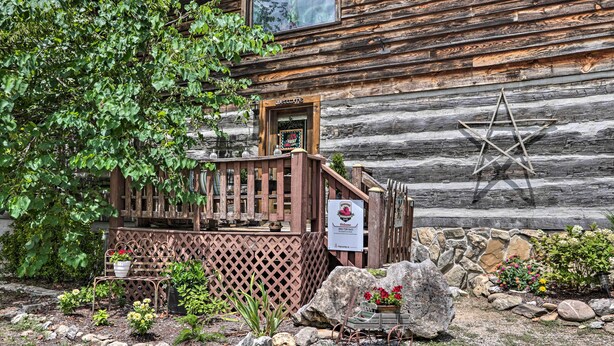 A rustic log cabin with a wooden porch, a decorative star, and a sign indicating a restaurant. - Fire Pit & Deck! Cozy Smoky Mtn Retreat on River (Townsend)