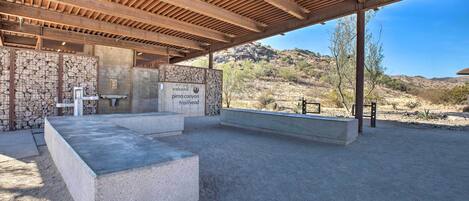 An outdoor covered area with a stone wall, a welcome sign, and a concrete seating area.