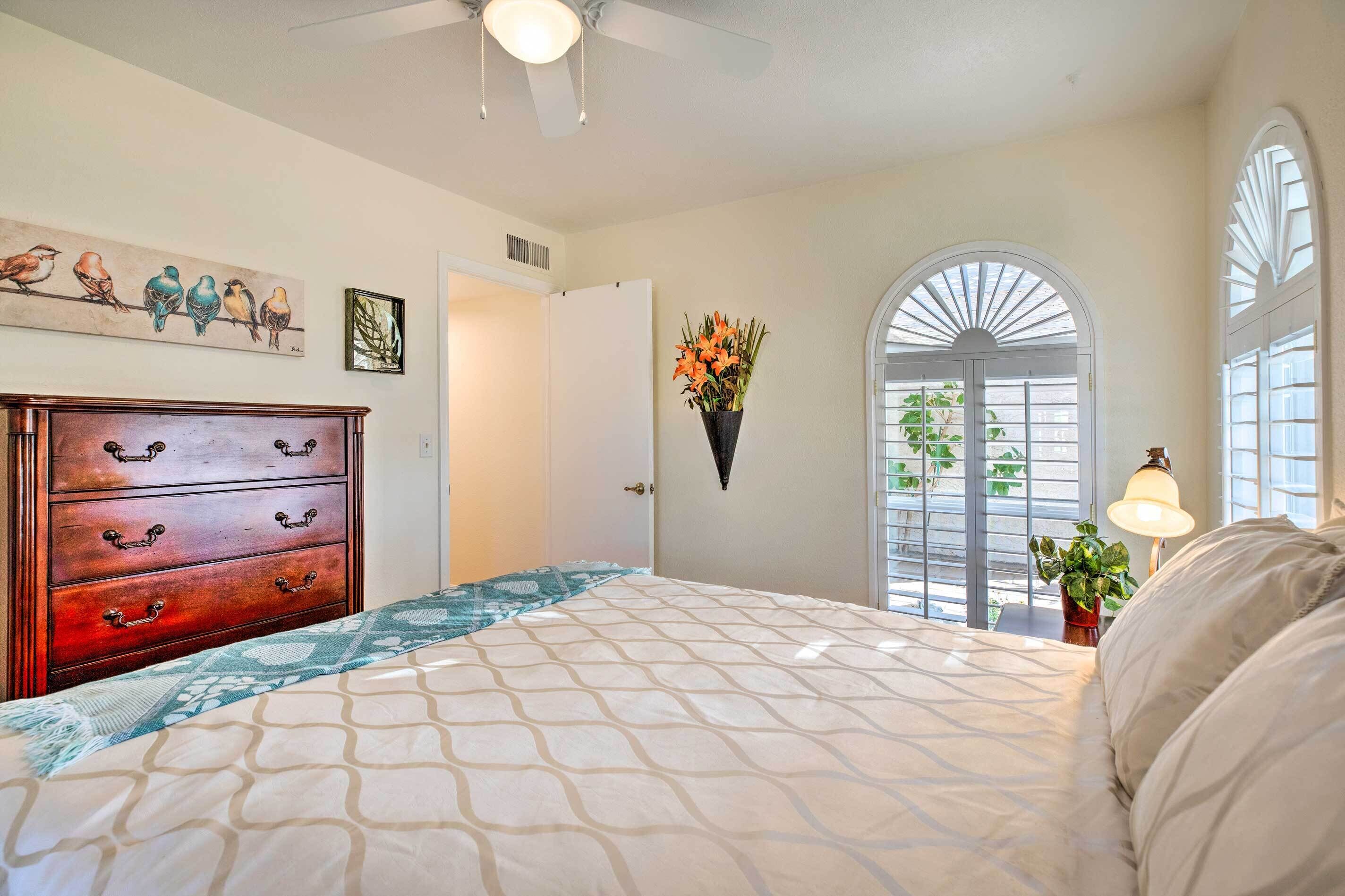 A bedroom with a bed, dresser, and artwork on the wall.