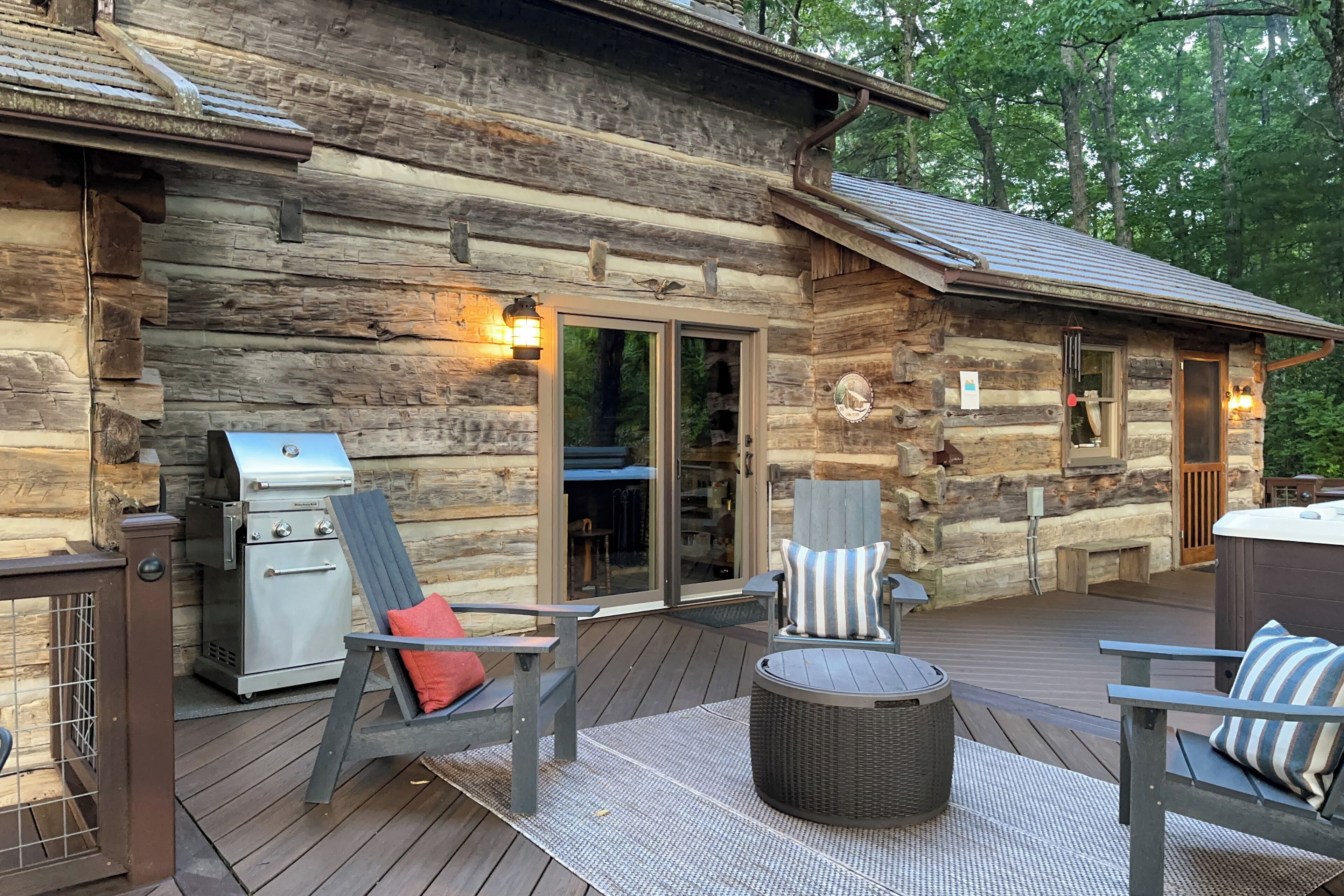 A log cabin with a deck, outdoor grill, and seating area.
