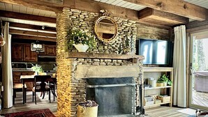 A stone fireplace with a TV above it, a wooden ceiling, and a stone wall.