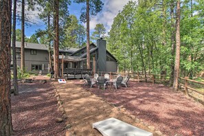 Une maison moderne dotée d’une terrasse, entourée de grands arbres et d’une clôture en bois.