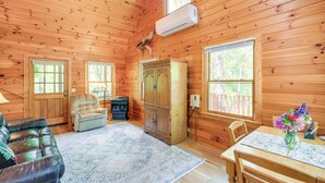 A wooden cabin interior with a sofa, armchair, dining table, and a cabinet. - Charming Cabin w/ Wraparound Deck in Blue Ridge! (Sparta)