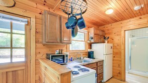 A wooden cabin kitchen with a stove, microwave, sink, and cabinets. - Charming Cabin w/ Wraparound Deck in Blue Ridge! (Sparta)