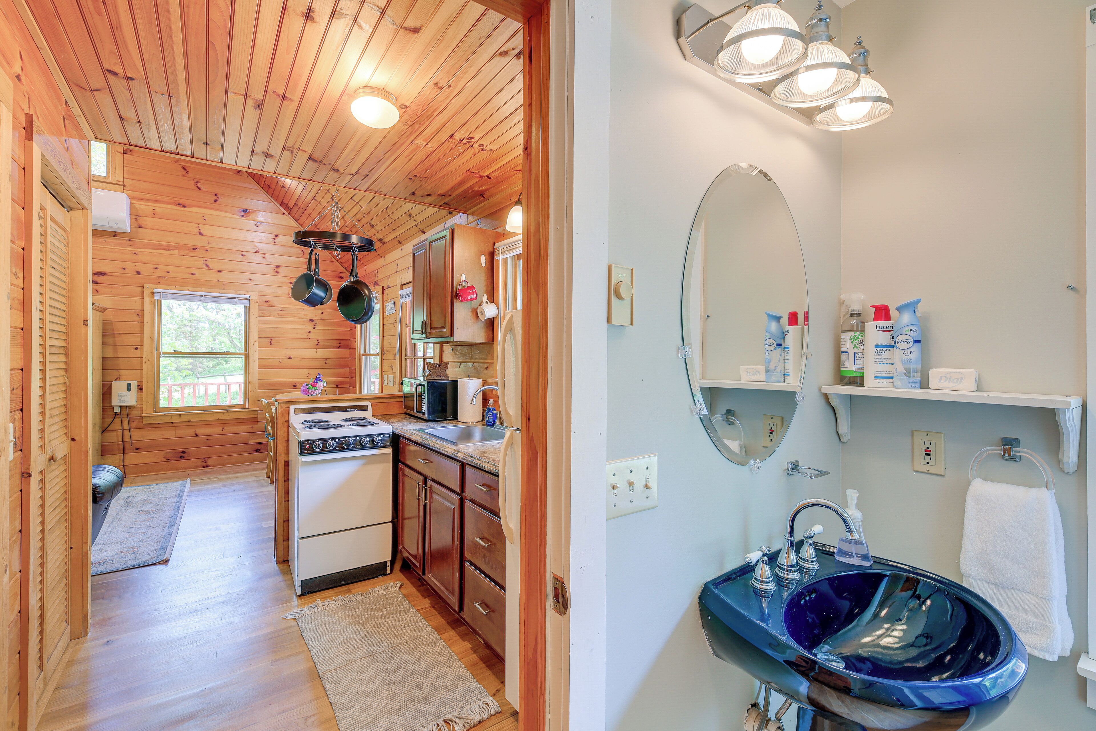 L’intérieur d’un chalet en bois comprend une cuisine, une salle de bain avec un grand miroir et un lavabo.