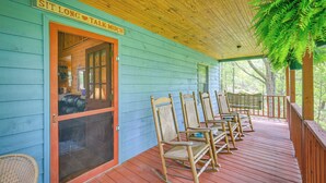 A porch with rocking chairs and a sign that reads "SIT LONG TALK MUCH". - Charming Cabin w/ Wraparound Deck in Blue Ridge! (Sparta)