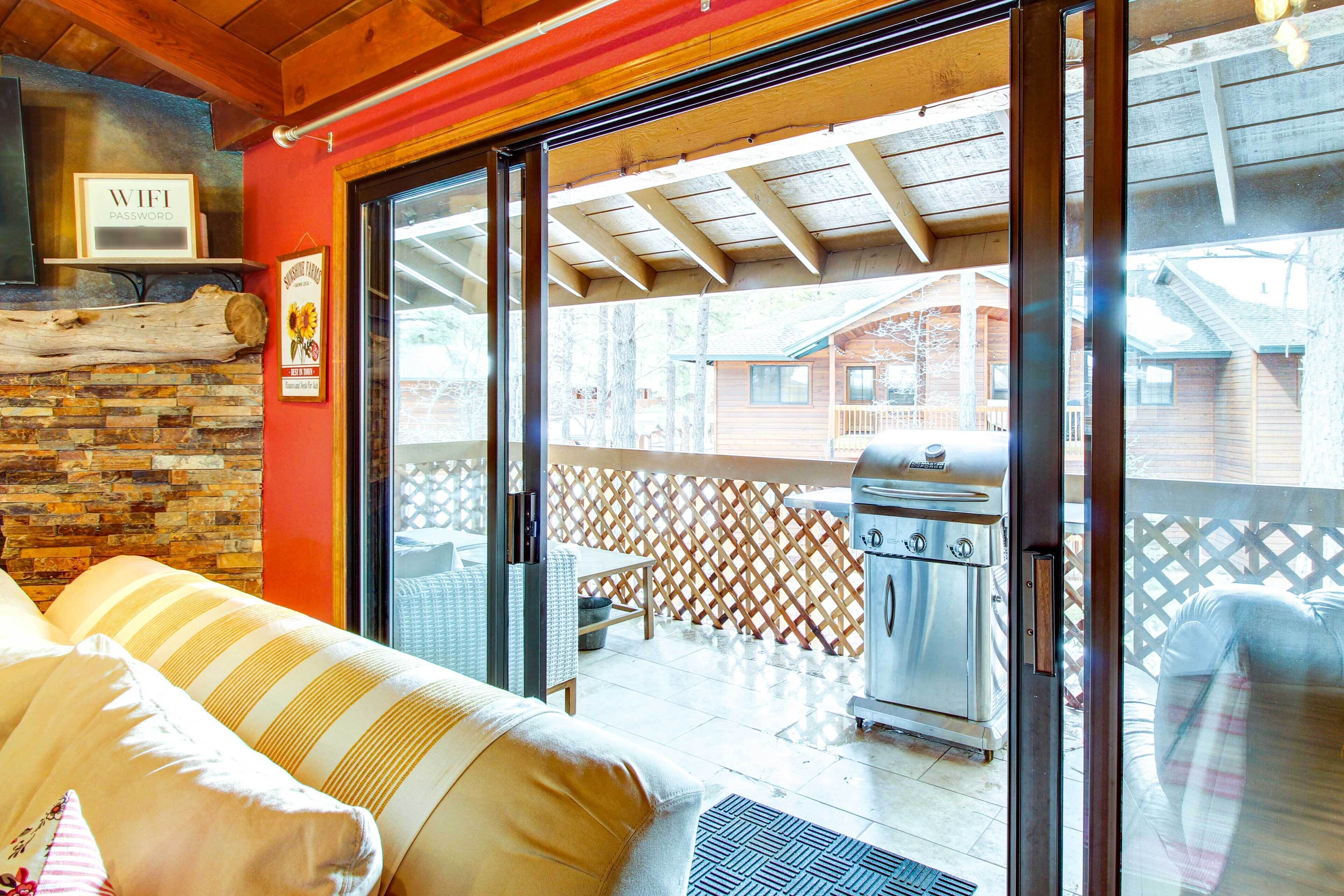A cozy room with a stone fireplace, a sliding glass door leading to an outdoor patio with a grill.